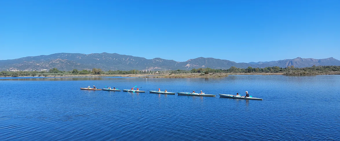 1_A Gruppo di persone in canoa su un lago limpido, circondato da montagne e natura incontaminata, durante un'attività outdoor.