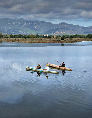 Due persone partecipano a escursioni nella laguna di Nora in canoa, pagaiando tra le acque calme del parco lagunare Nora, immersi nell’ecosistema lagunare.