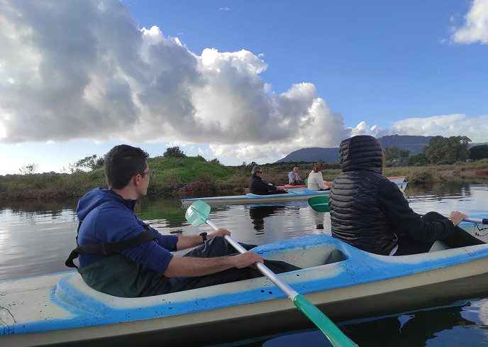 1_B Gruppo di persone in canoa su un lago calmo, circondato dalla natura e colline, durante un’escursione all’aria aperta.