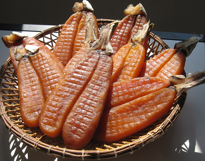 4_D Uova di muggine essiccate al sole disposte in un cestino intrecciato, pronte per diventare bottarga, una specialità tradizionale della cucina mediterranea.